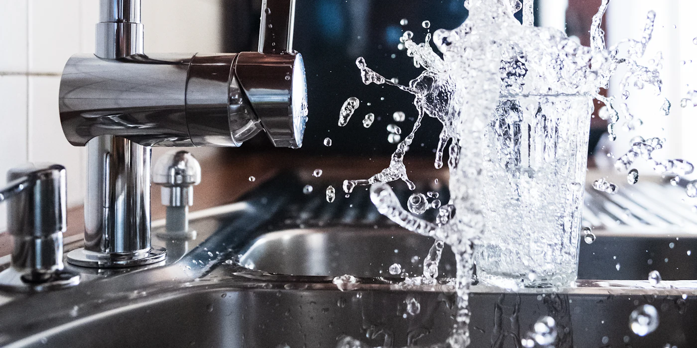 Tap water filling a glass at a kitchen sink